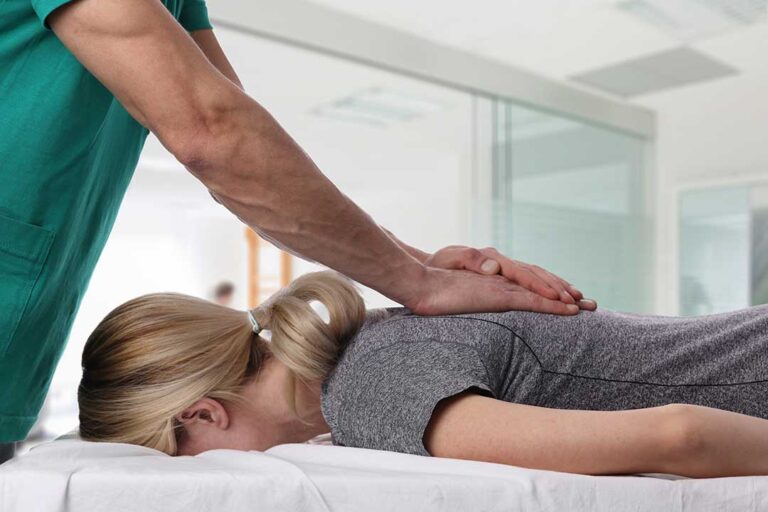 A therapist uses a stainless steel instrument to treat a person's forearm in a clinical setting.